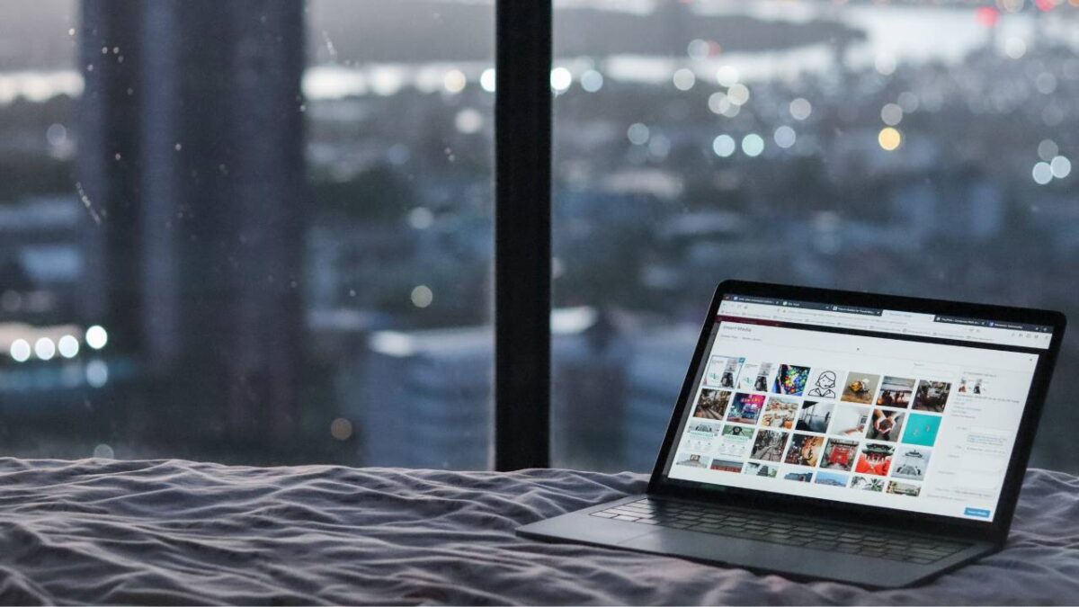 A laptop placed on a bed with a view of the city in the background
