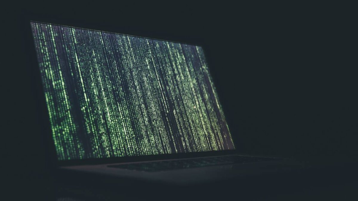 A laptop with green code lines in the dark