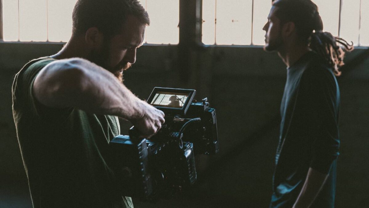 A man filming another man with a large camera