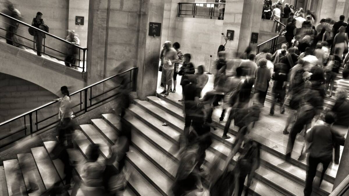 A lot of people walking up and down stairways in a public space