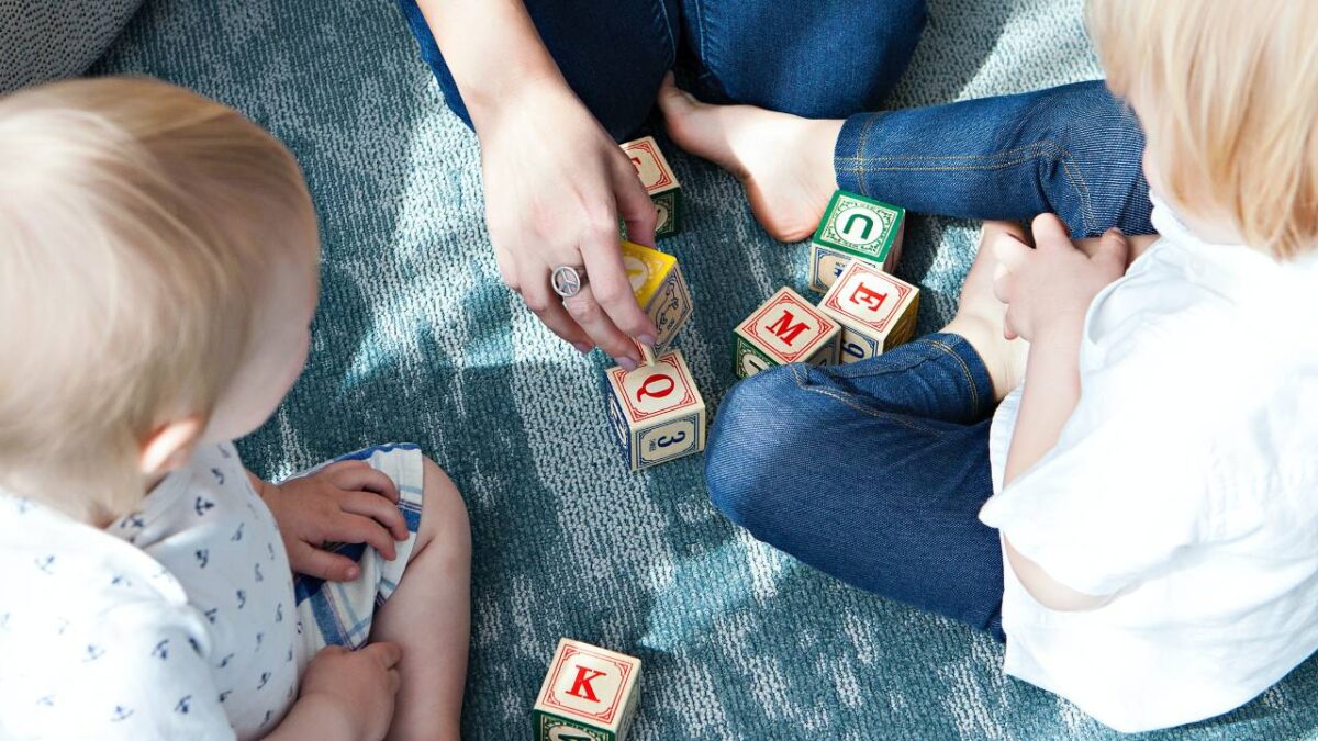 A mother using wooden cubes to play with her kids