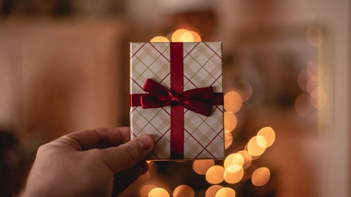 A person holding a small Christmas gift