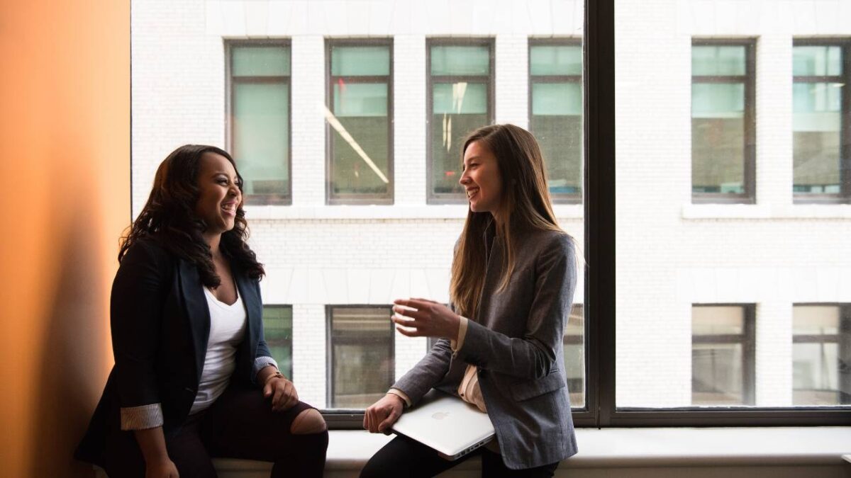 Two female employees talking near the window