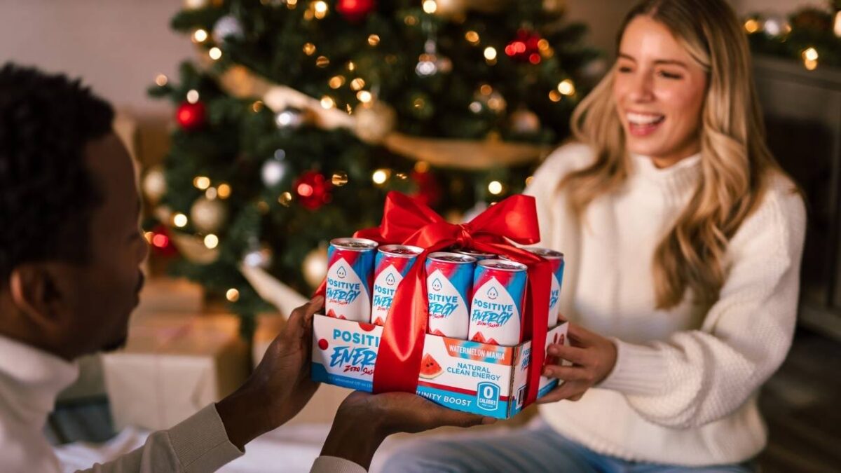 A woman giving a pack of energy drinks to a man as a Christmas gift