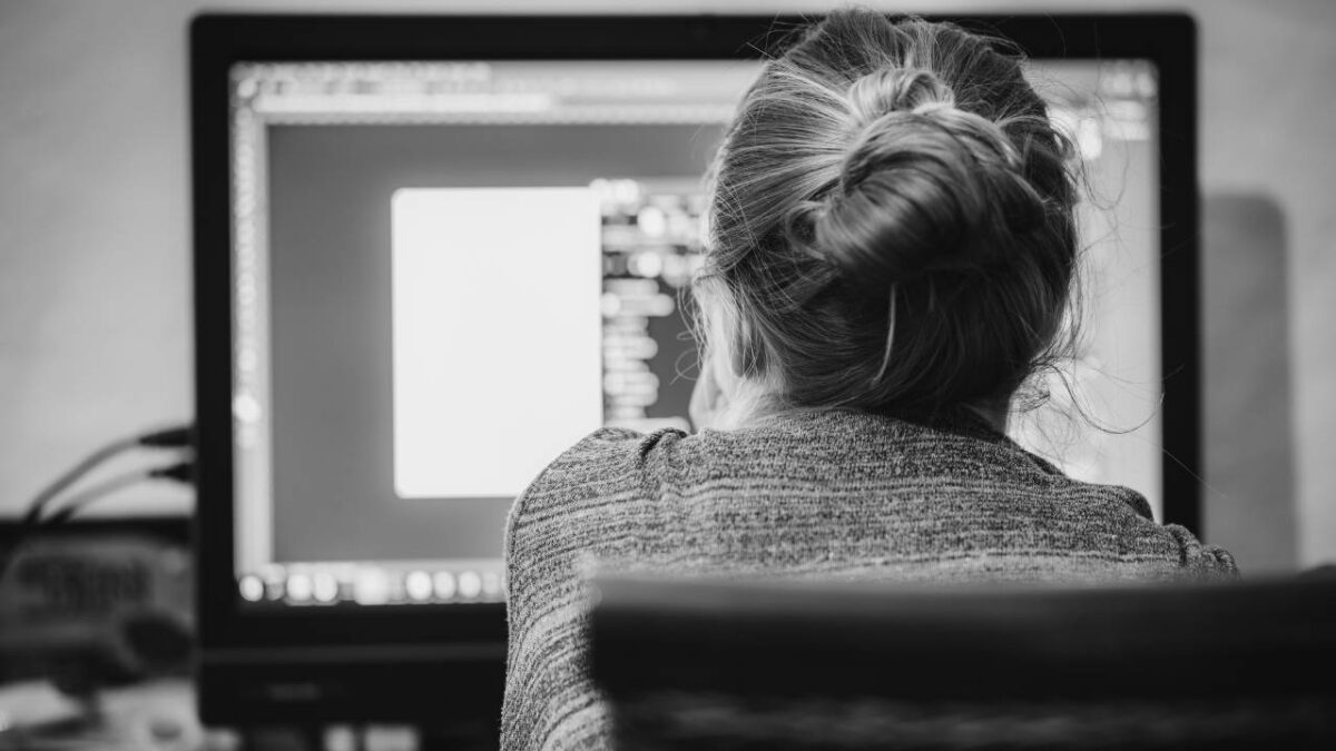 A black and white photo of a woman looking at the computer screen