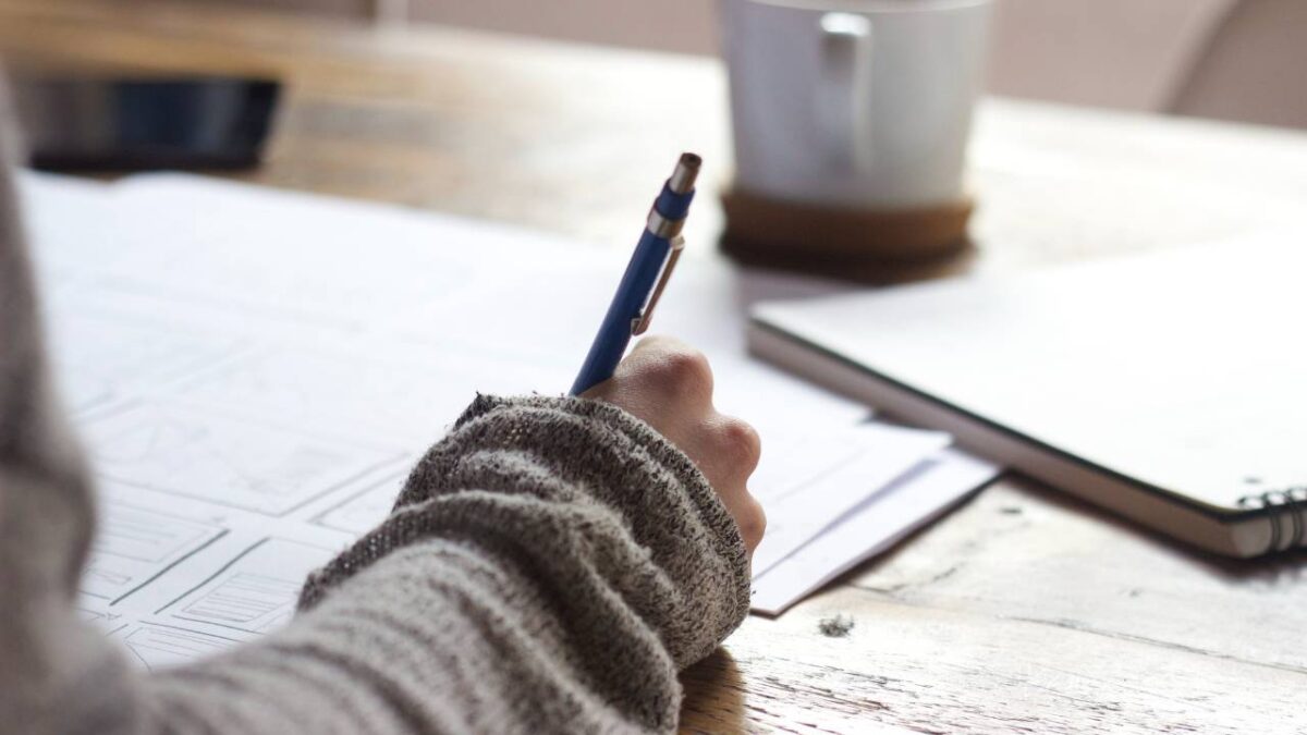 Woman using a pen to write in a notebook