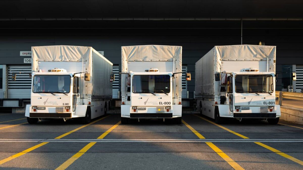 Three white trucks parked on a parking lot