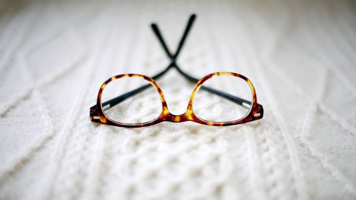 A pair of reading glasses placed on bed's linen