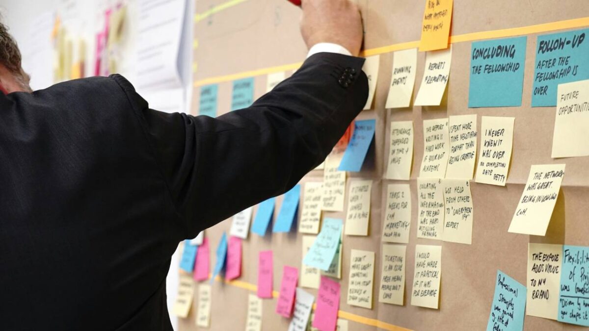 Man pinning various sticky notes to a cardboard panel